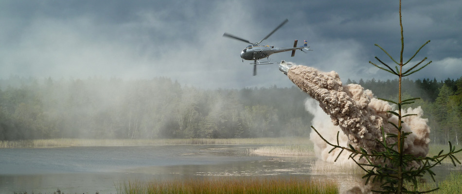 Helikopter flyger över kroktjärn och släpper ut kalk i sjön. 