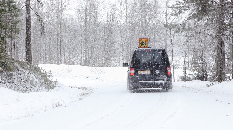 Svensk skolskjuts på vinterväglag med pågående snöfall.